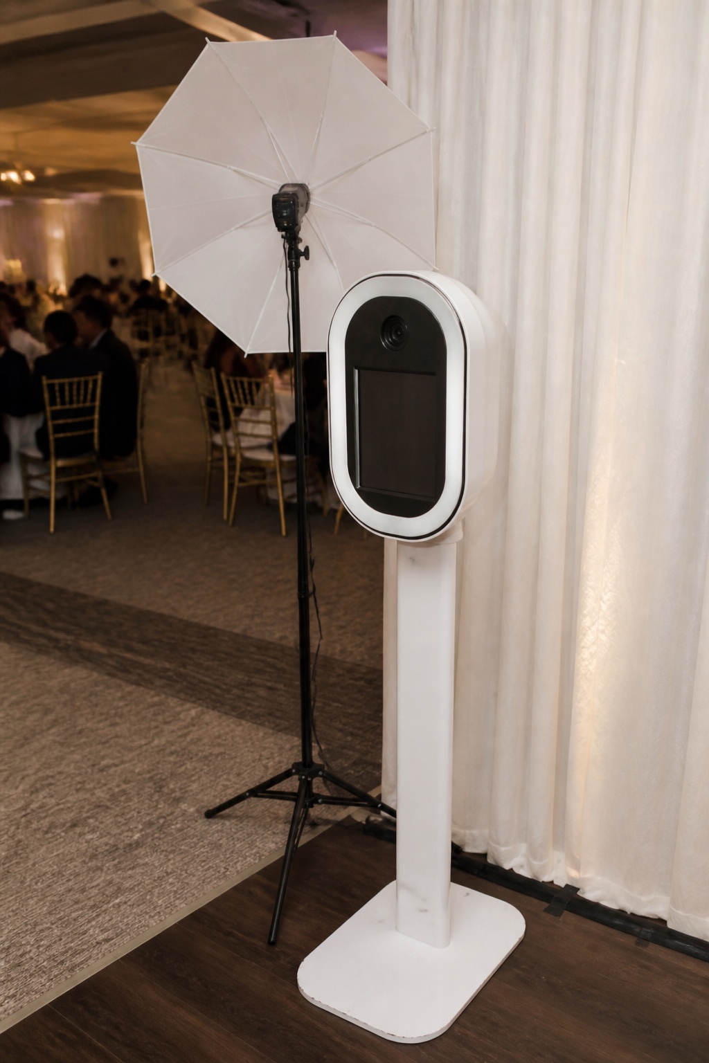 Photobooth blanco tipo cápsula con cámara, pantalla, poste delgado, base redonda y paraguas profesional